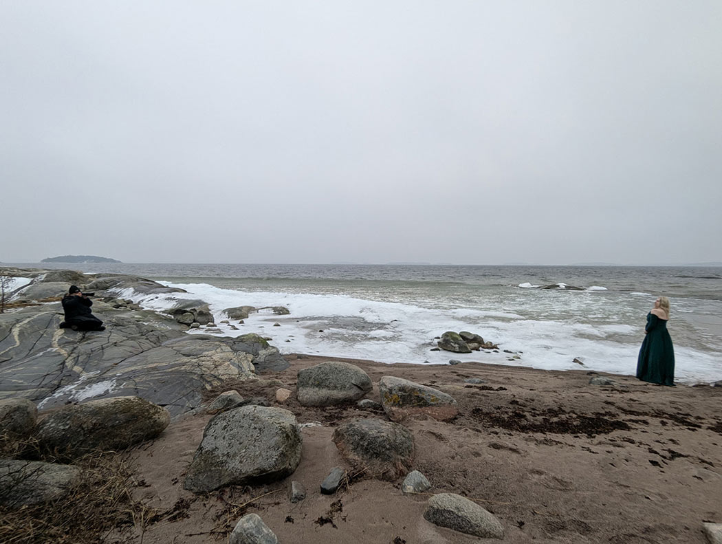 Gravidfotograf Linda Holmkratz fotograferar en gravid kvinna på stranden vid havet. Bilden är tagen av den blivande pappan.