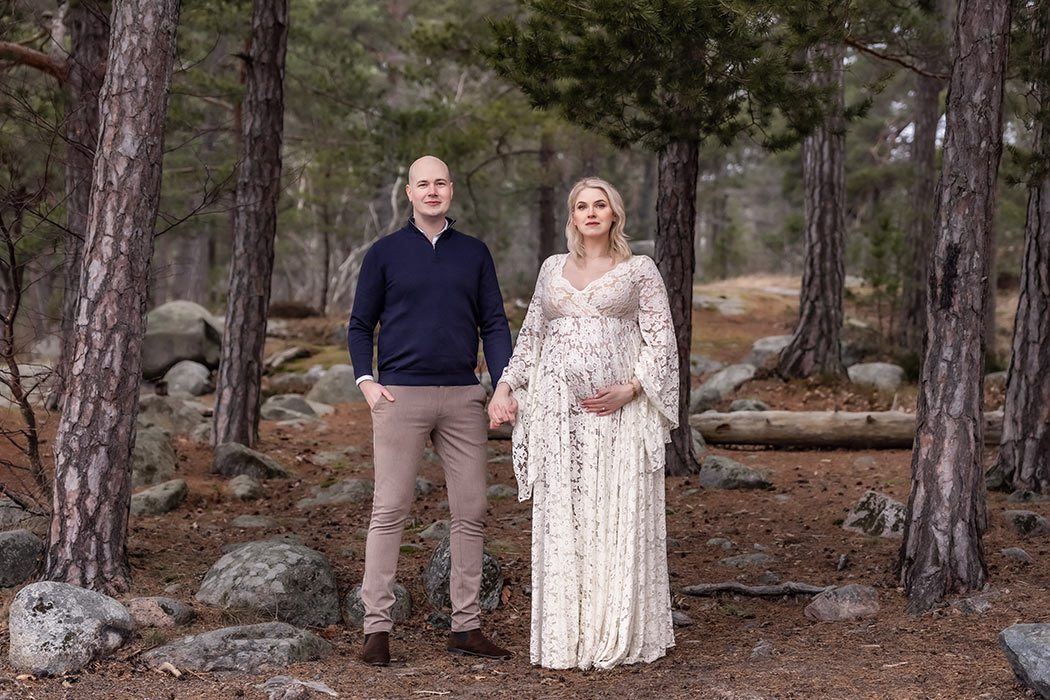 Gravidfotografering med vackert par i en barrskog.