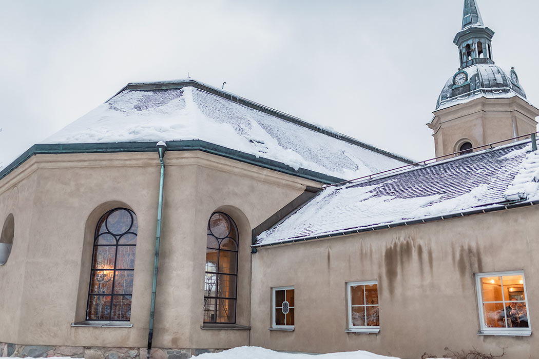 Norrtälje kyrka i vinterskrud och kvällsmörker.