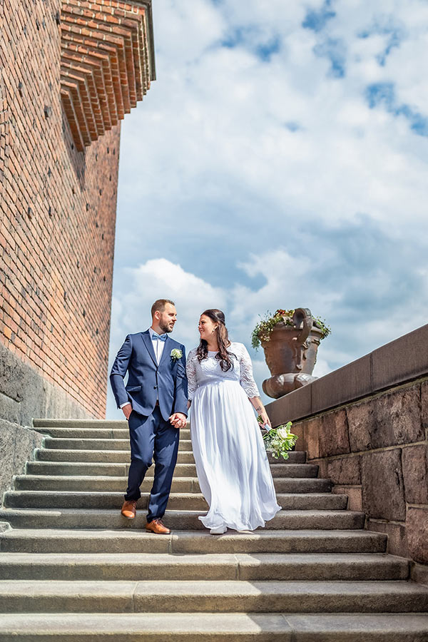 Bröllopsfotografering av ett bröllopspar som går ner för trappor utanför Stockholms stadshus.