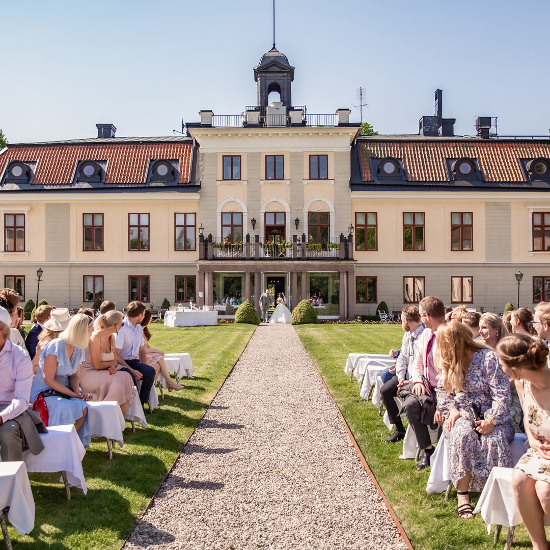 Brudparet kommer ut från Södertuna Slott och går mot gästerna och vigselplatsen i slottsparken.