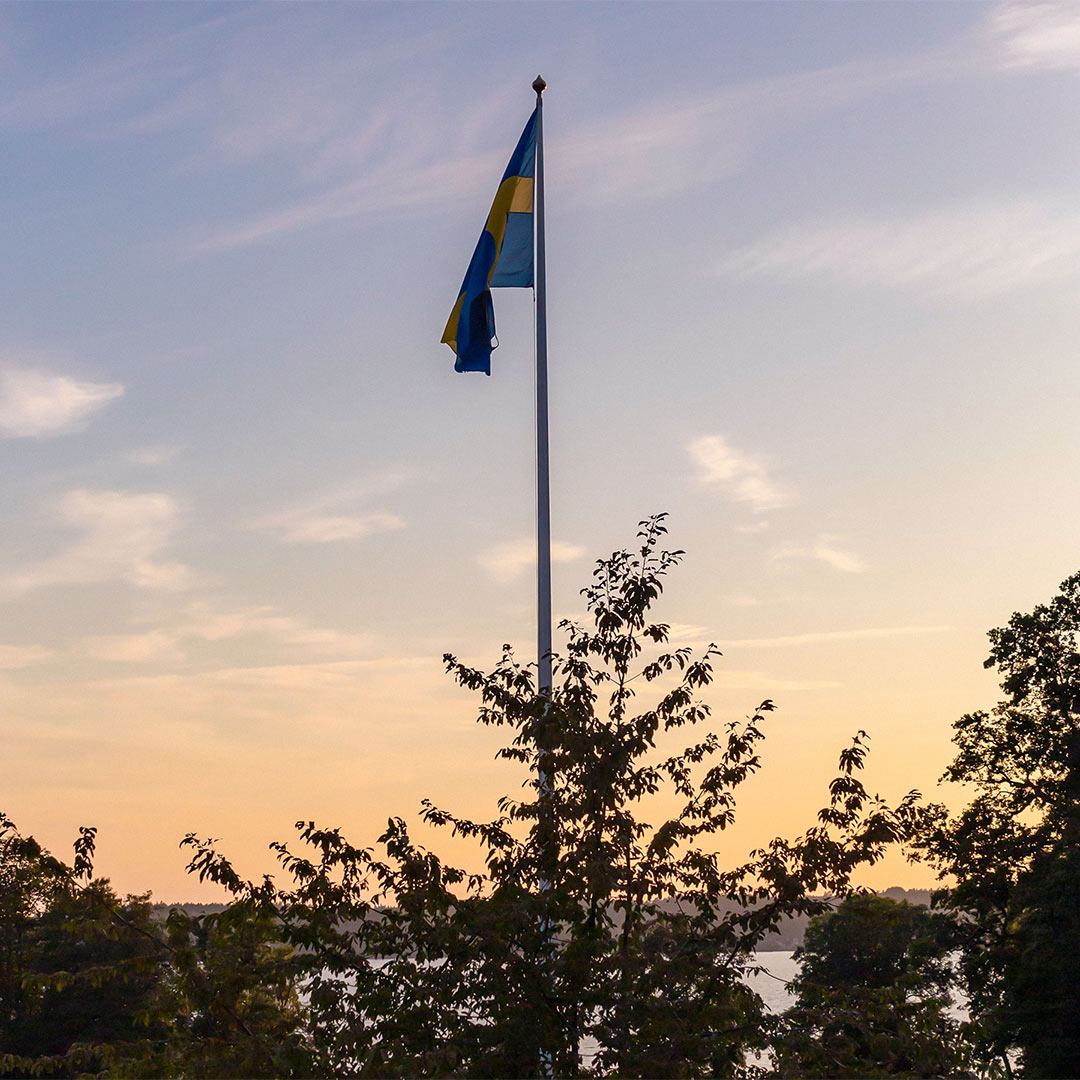 En flagga vajjar i vinden i solnedgången.