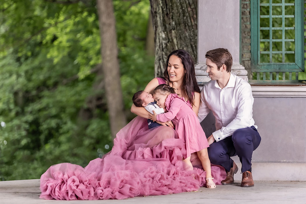 Familjefotografering med två barn i Ekotemplet i Hagaparken om sommaren. Storasystern kramar om sin lillebror.