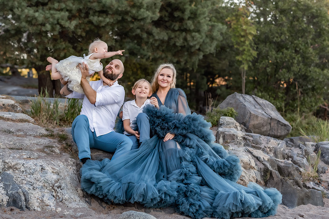 Familjefotografering i september vid havet. Familjen sitter på en stor sten och är fint matchat i blått och vitt.