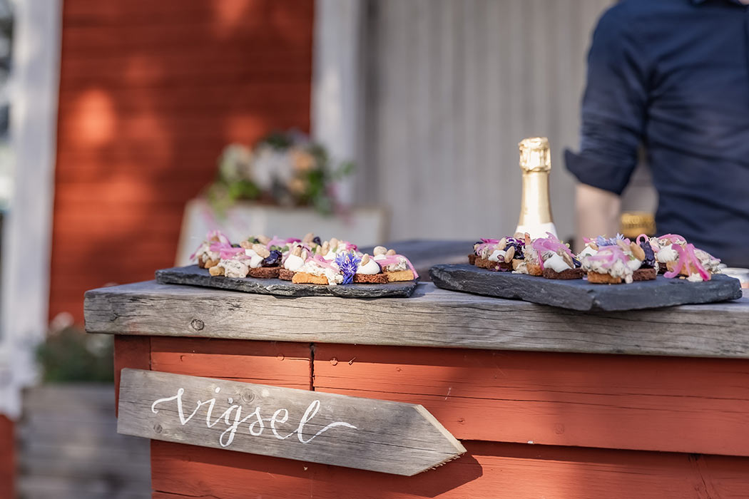 Fat med vackra snittar står på en bar i falu rödfärgat trä. Under hänger en träskylt där det står vigsel.