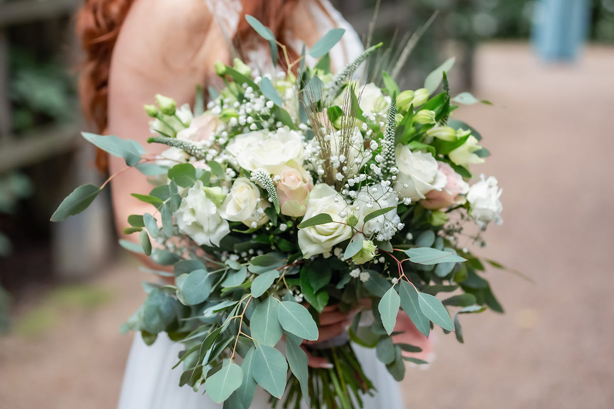 En vacker bröllopsbukett med vita rosor och eucalyptus.