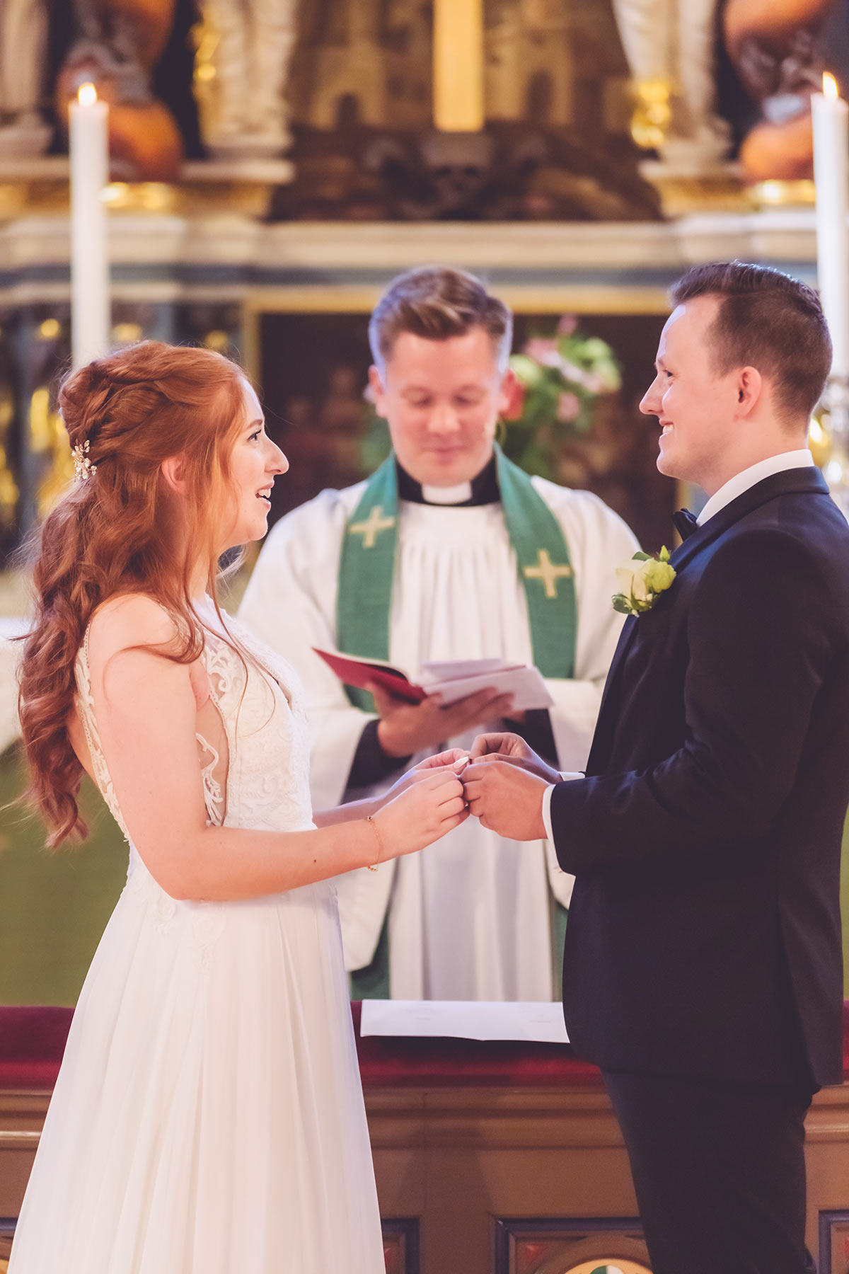 Bruden och brudgummen står i kyrkan framför prästen och byter ringar.