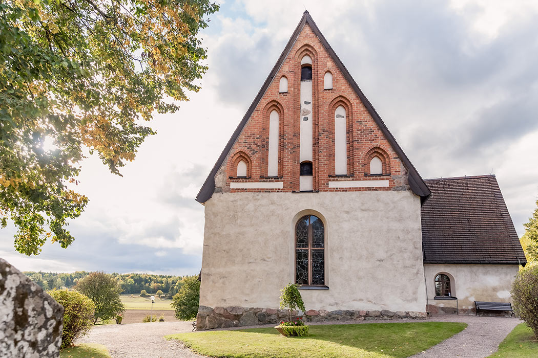 S:t Stefans kyrka en vacker höstdag. Solen skiner in mellan grenarna på ett träd.