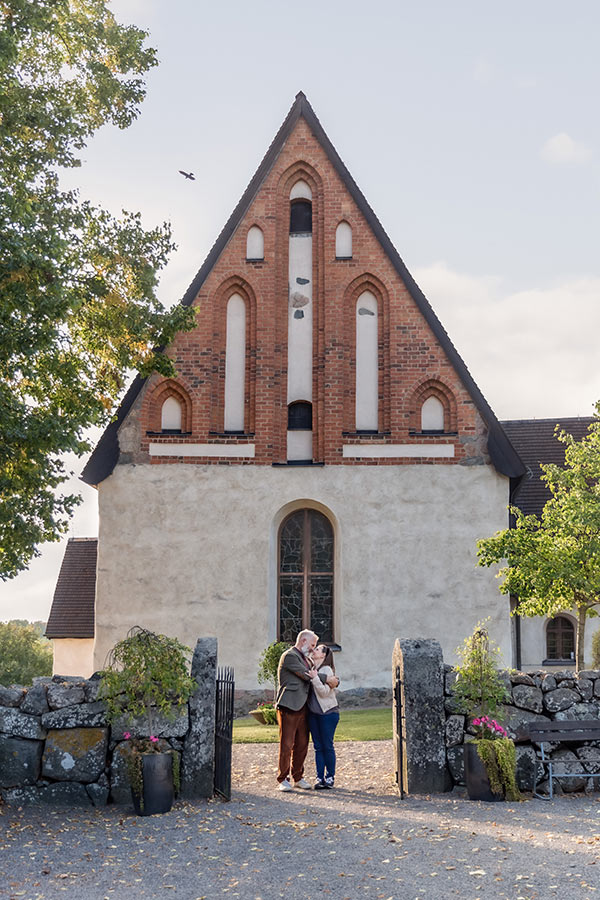 Ett par står framför S:t Stefans Kyrka i Knivsta och håller om varandra.