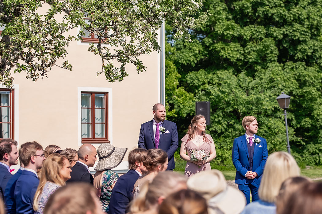 Brudföljet står framför ett hav av gäster under vigseln på Södertuna slott.